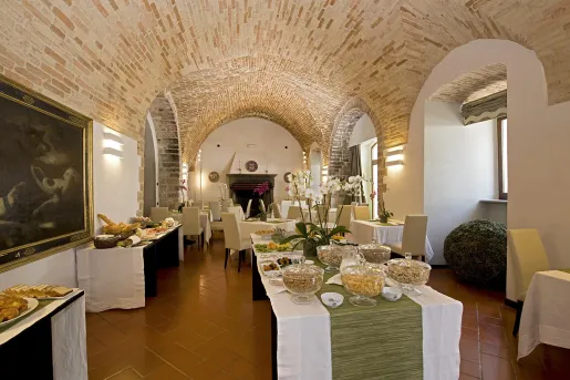 Restaurant dining hall with tables full of bread and food on trays, with large stone ceilings