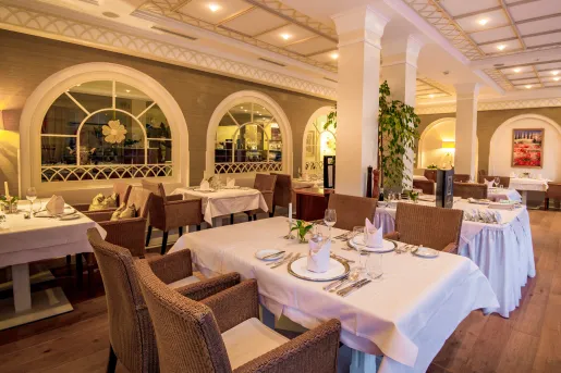 Restaurant dining area with woven chairs and tables with white cloths