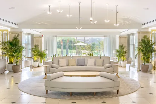 Large room with large, cushioned sofas and large windows in the back