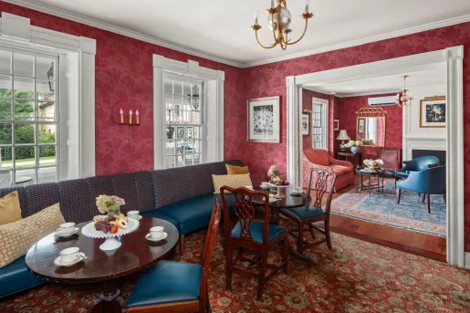 Hotel lobby with red walls and cushioned chairs and wooden, circular tables