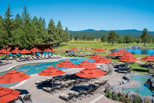 Outdoor pool area with reclining chairs and red umbrellas