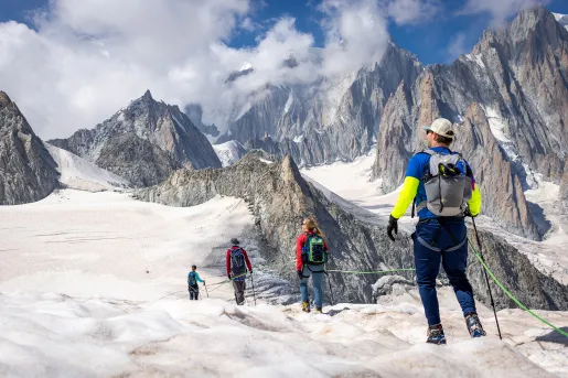 Group of hikers walking along a guardrail on top of a snowy mountain