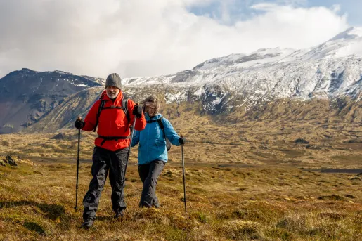 Man and woman with hiking poles, walking in an open valley