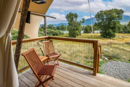 Outdoor, wooden patio with two wooden chairs looking out to a valley