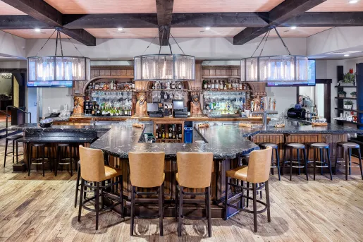 Indoor bar and lounge with a horseshoe-shaped marble counter and alcohol along the walls