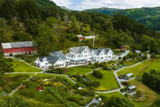 Exterior, sky view of long, white hotel complex with a forest in the background