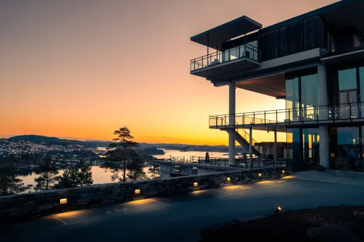 Sunset view of a large building with glass balconies looking out to a lake