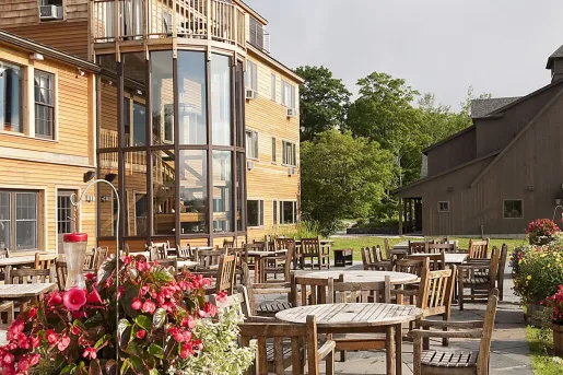 Exterior view of yellow hotel building with dining tables in front