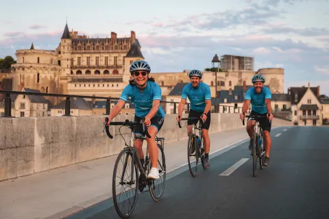 Three guests cycling in French town, Château Royal d'Amboise in background.