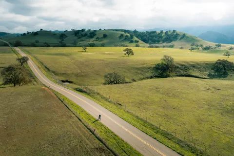 Vast, open California road with s very small bicyclist in foreground.