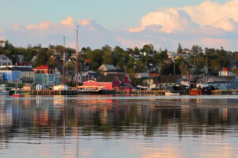 Wide shot of seaside town at sunset, vibrant red houses scattered throughout.