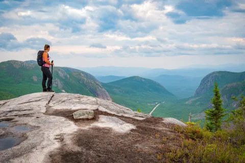 Woman at the top of a rock looking down at grassy hills