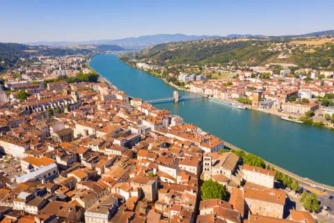 Brown and white buildings connected by a single bridge over a river