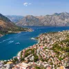 Bird's eye of Croatian riverside city, mountains all around, boats in river.