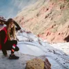 Backroads guest crouching in snow on hiking trail in Peru.