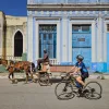 Woman riding a bike while looking at a man on a horse carriage