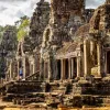 Woman with arms open next to ancient temple ruins