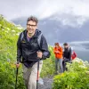 Man with walking sticks climbing up grassy hill