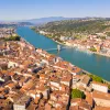 Brown and white buildings connected by a single bridge over a river
