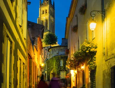Two guests walking down French alleyway, church spire in front of them.
