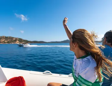 Two guests on boat, waving to another.