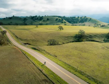Vast, open California road with s very small bicyclist in foreground.