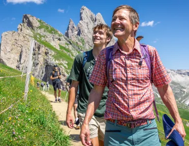 Two men smiling while looking up to the sky, while walking on a dirt trail