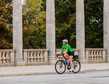 Woman in a green shirt, riding a bike on a road