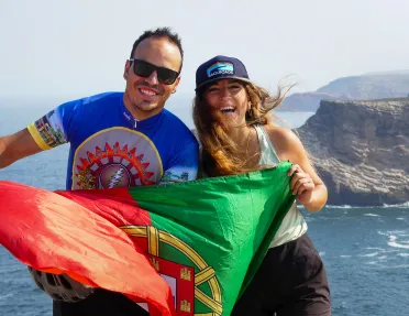 Man and woman smiling while holding up a Portugal flag